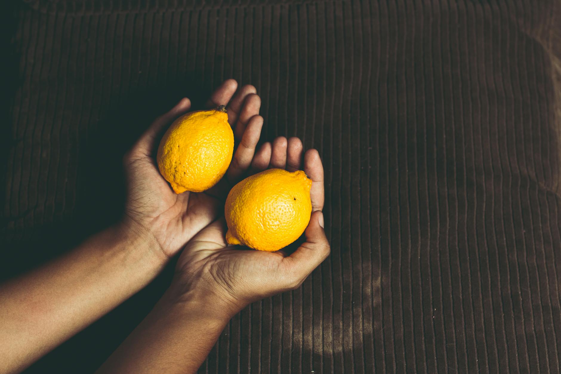 Two women smiling together holding fresh lemons, representing joy and openness about pleasure