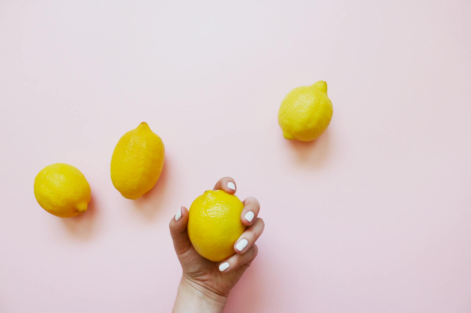 A hand holding a fresh lemon against a bright yellow background, symbolizing renewal and recovery.