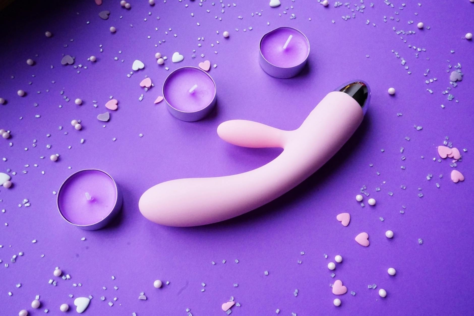 Woman holding blue and pink silicone vibrators in a contemplative manner