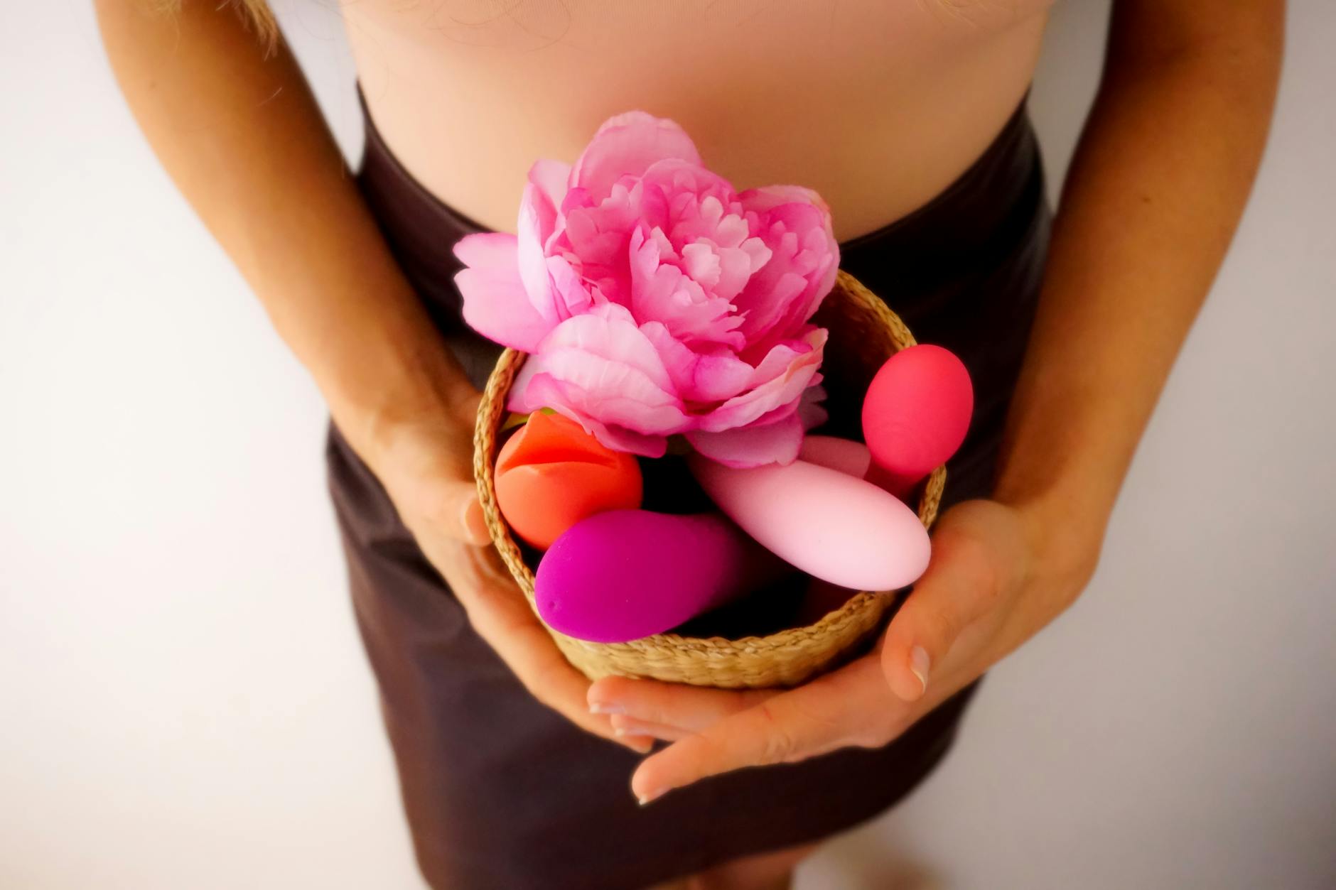 A basket of colorful vibrators and intimacy tools displayed with fresh flowers