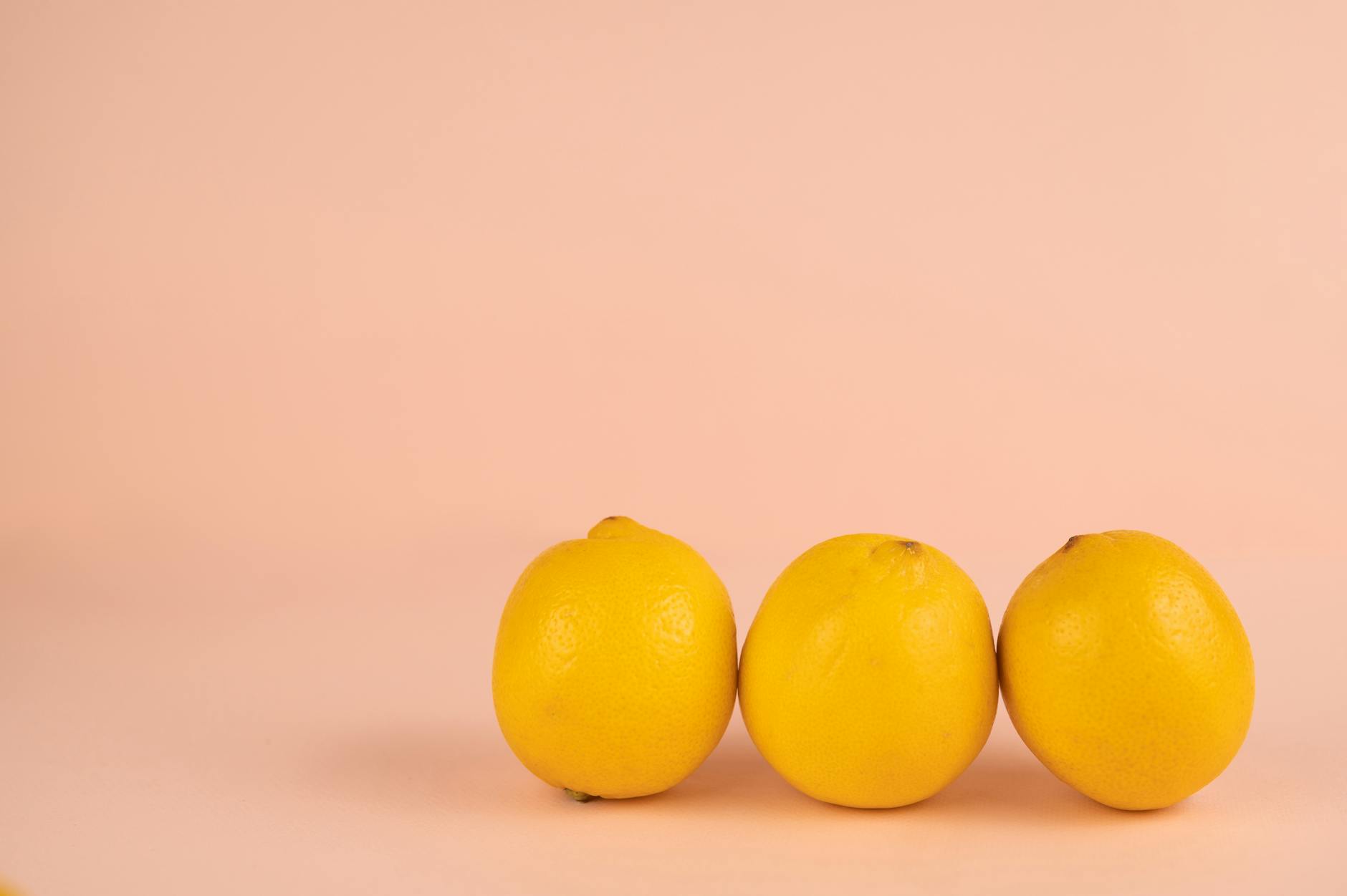 Close-up of a hand holding an orange vibrator against a minimalistic purple backdrop